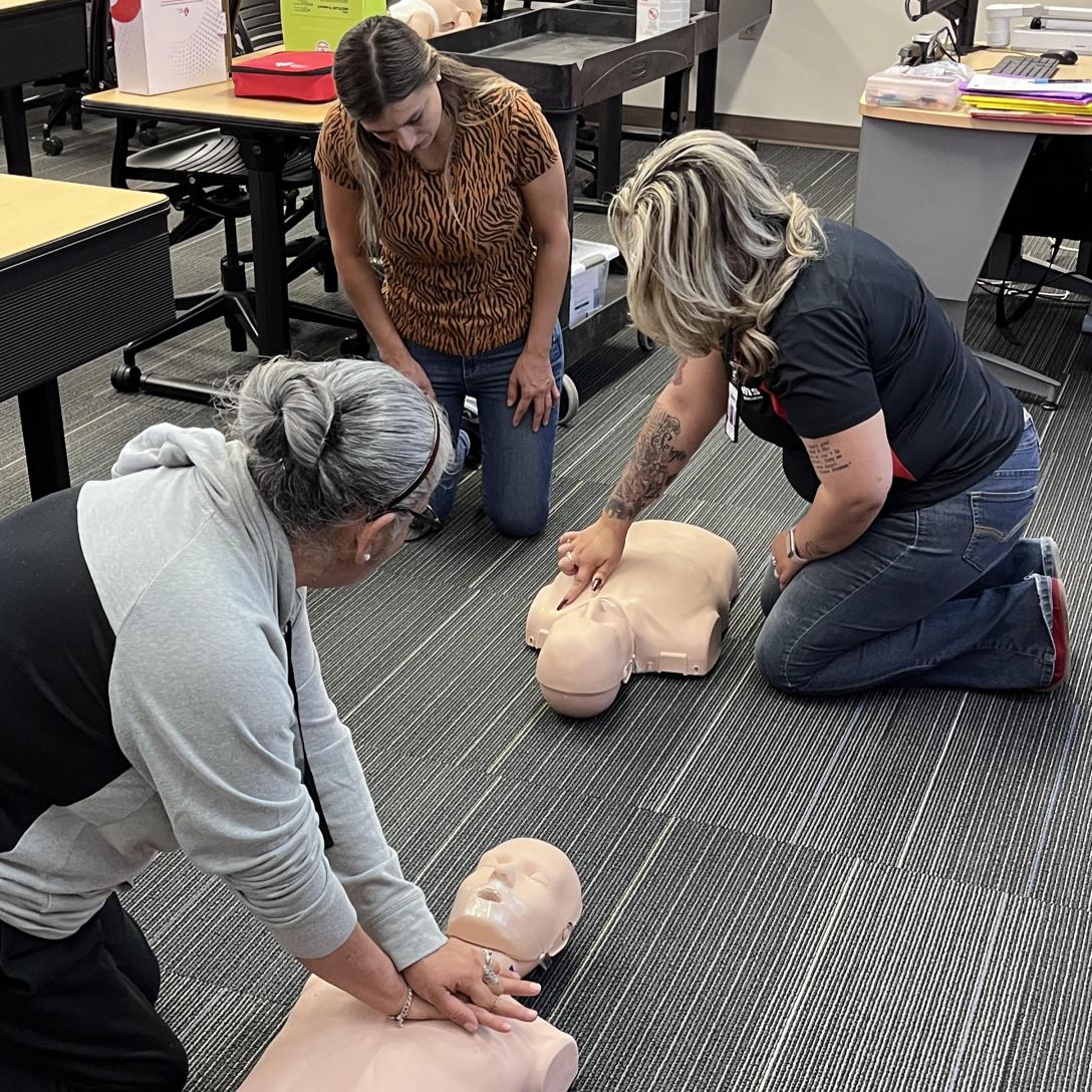 Students in the Spanish language Heartsaver class practice CPR on dummies.