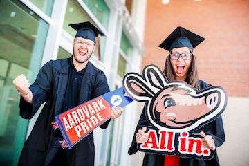 Aims graduates in caps and gowns showing excitement about commencement