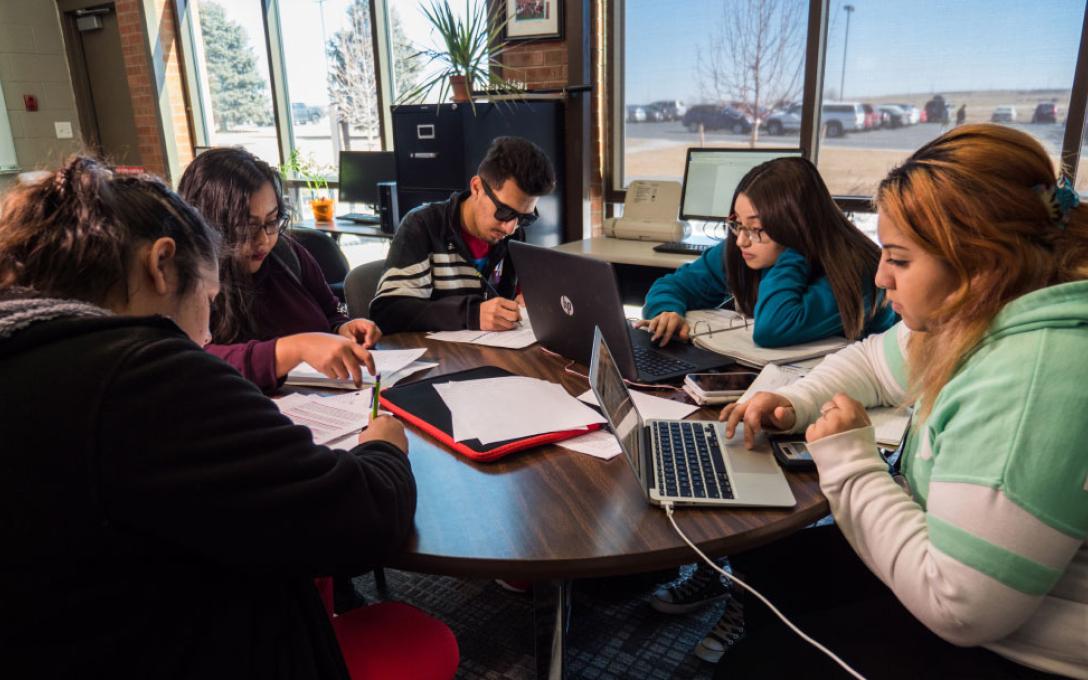 Aims students working at a round table in a classroom