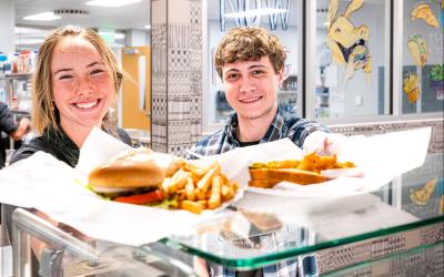 Two Atry's Bistro employees hold up food to the camera for a photo.