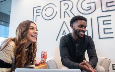 Two students in the lounge laughing and talking while sitting on couches