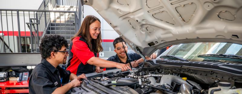 An instructor and students work on a Ford truck engine in the Ford ASSET automotive degree program