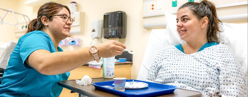 Two nurse aide students practice during class at Aims Community College.