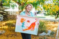 Aims alumna Mel Calderon holding one of her paintings