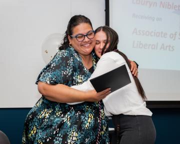 women huging at awards ceremony