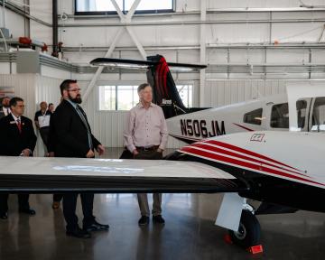 Hickenlooper and Aims staff looks at airplane in hanger