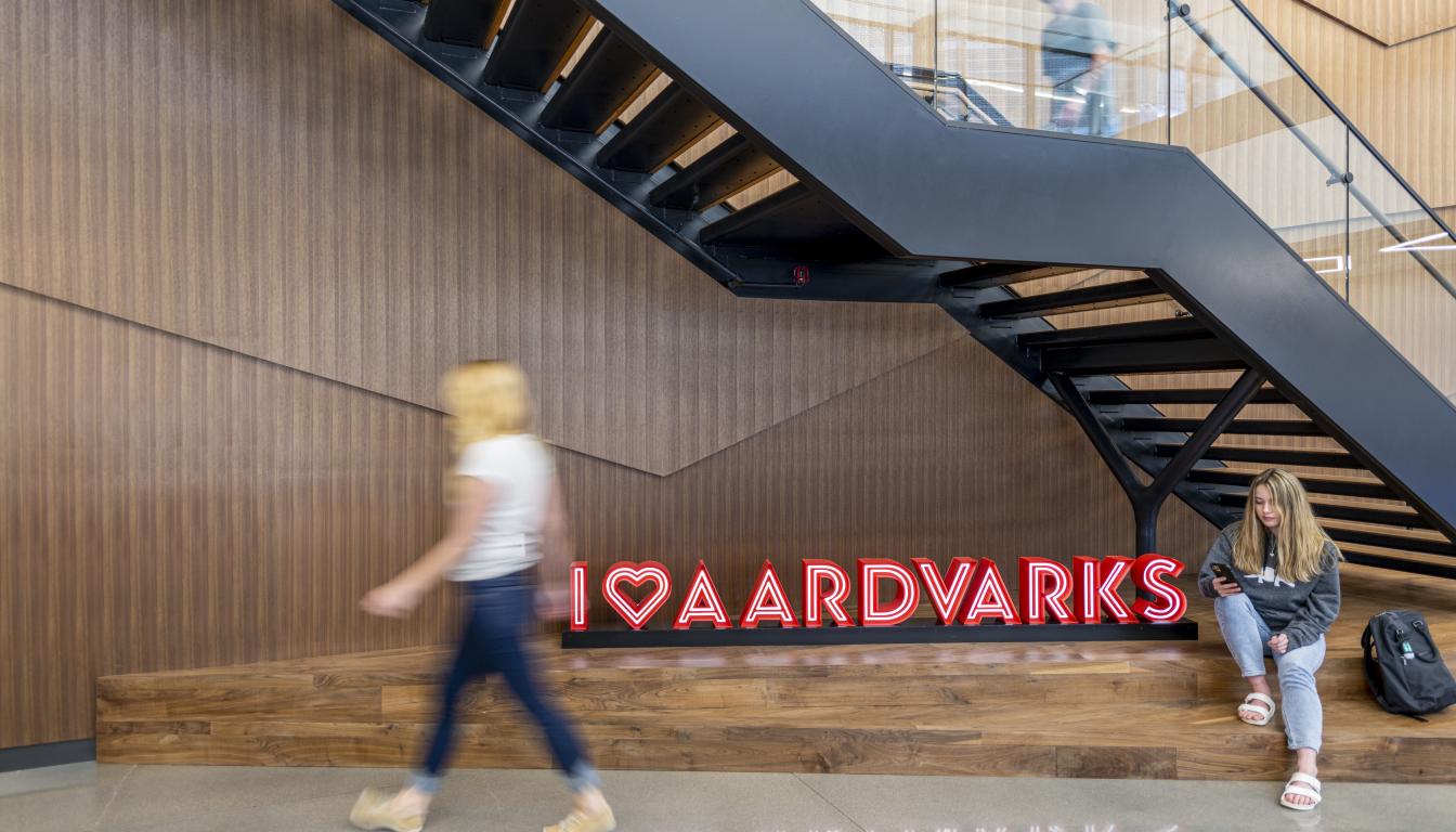 Two Aims students in front of the I Heart Aardvarks sign on the Welcome Center staircase