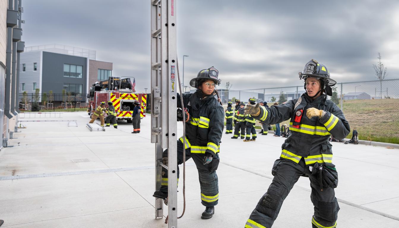 Two firefighting students use a ladder at a training exercise